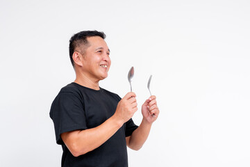 Middle aged Asian man smiling, holding a spoon and fork, isolated on white