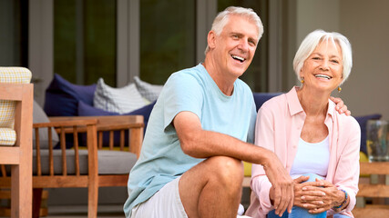 Loving Senior Couple Sitting Outdoors On Deck At Home Together