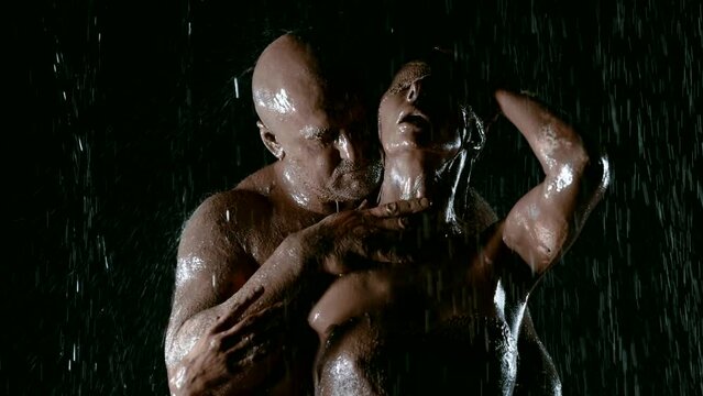 In this sinister setting against a black background, a touching saga of passion and affection is solved, where a man with a muscular physique and his gorgeous wife, plastered with clay