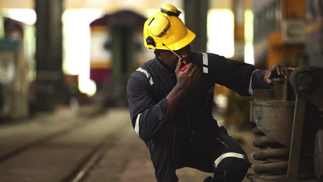 Railway technician in uniform and helmet inspect the train wheels removed from the locomotives in the train workshop.