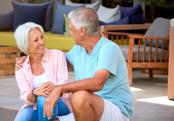 Loving Senior Couple Sitting Outdoors On Deck At Home Together