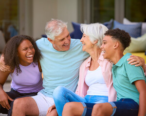 Multi Racial Family With Grandparents Talking To Teenage Grandchildren Sitting On Deck At Home