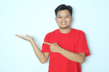 Young Asian man smiling while pointing to his open right hand palm. Wearing red t-shirt