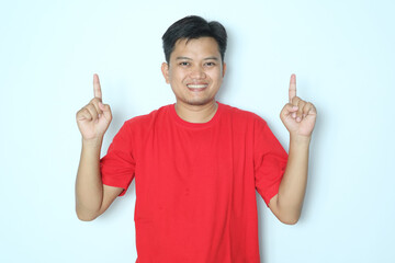 Young Asian man smiling happy and pointing both hands up. Wearing red t-shirt