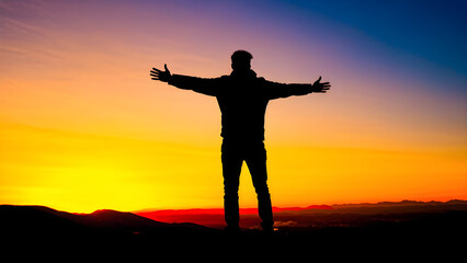 Fototapeta premium Silhouetted Dreams: Traveler Reaches the Peak, Arms Open to the Sunset. Adventure's Reward. Man Silhouetted Against a Fiery Sunset. generative AI