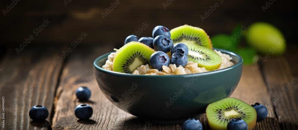 Poster A nutritious breakfast of oatmeal with blueberries and kiwi is beautifully presented on a wooden table leaving ample space for copy in the image