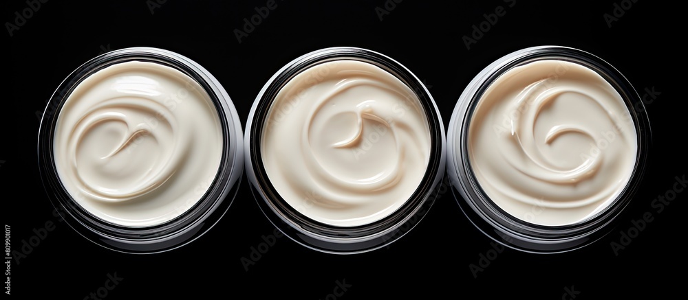 Poster a top view of three isolated face cream jars on a black background with copy space for an image