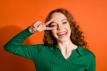 Photo of good mood funky lady dressed green shirt showing v-sign stick out isolated orange color...