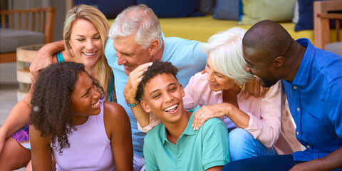 Three Generation Family Laughing And Smiling Sitting Outdoors At Home On Deck Together