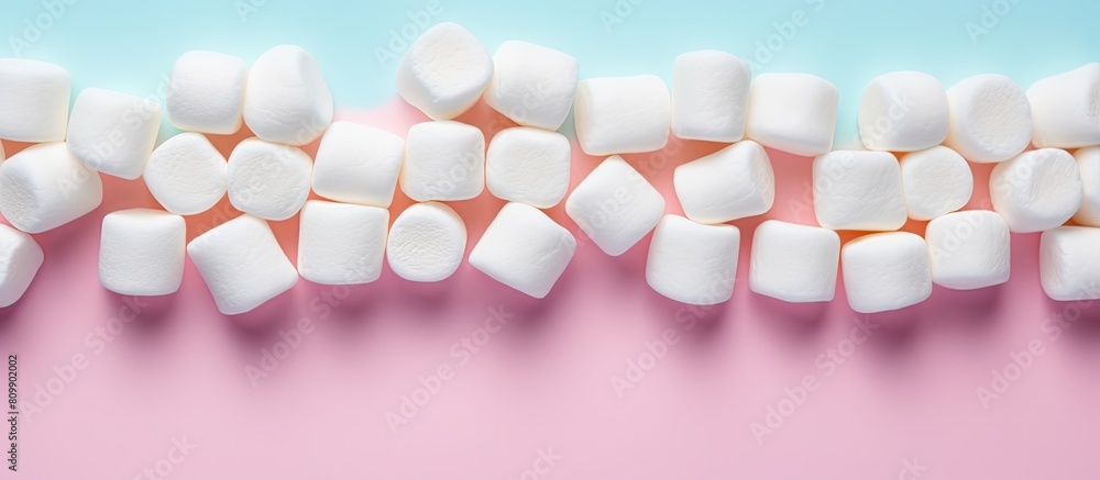 Aufkleber marshmallows arranged in a flat lay composition with a copy space frame on a pastel pink and blue ba