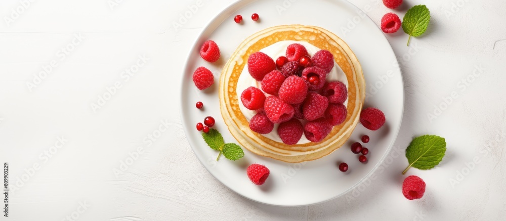 Poster top view of fluffy pancakes topped with fresh raspberries presented on a white ceramic plate with am