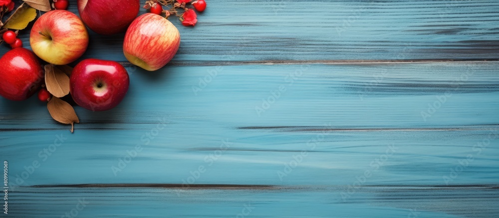 Aufkleber A copy space image featuring a rustic wooden board adorned with a heart leaves and an arrangement of vibrant red apples set against a backdrop of a serene blue background