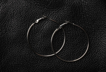 Silver hoop earrings on black leather background
