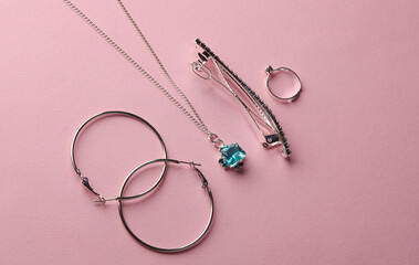 Silver jewelry accessories on pink background. Earrings, hairpin, Pendant and ring. Top view. Flat...