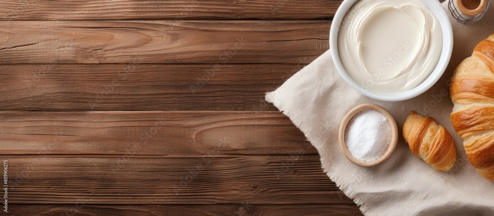 Poster on a wooden table there is a top view of a fresh croissant placed on white fabric additionally there
