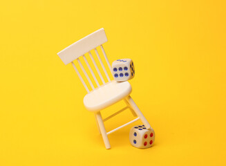 Miniature of a chair with dice, yellow background. Gambling addiction