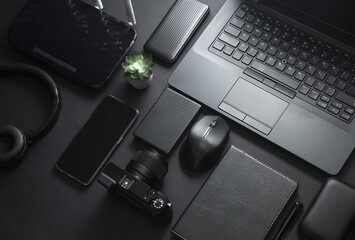 Modern black gadgets and accessories. Laptop, camera, smartphone, stereo headphones, notepad,...