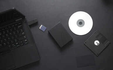 Outdated and modern digital storage media with laptop on black background