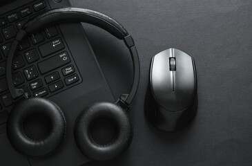 Laptop with stereo headphones and mouse on black background