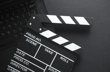 Movie clapperboard with laptop on black background