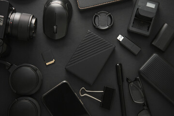 Flat lay composition of Modern black gadgets and accessories on a dark black background. Top view