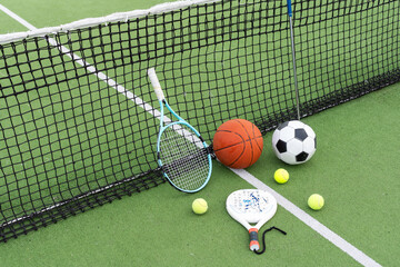 A variety of sports equipment including an american football, a soccer ball, a tennis racket, a...