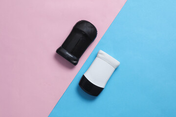 Black and white antiperspirant tubes on blue pink background. Sweat protection. Top view