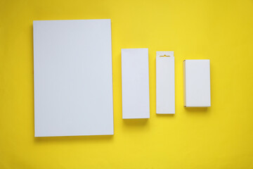 Different shapes of white cardboard boxes for products on a yellow background. Mockup for design
