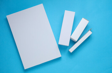 Different shapes of white cardboard boxes for products on blue background. Mockup for design