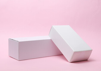 Different shapes of white cardboard boxes for presentation products on pink background. Mockup for design.