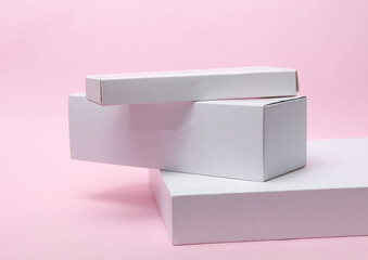 Different shapes of white cardboard boxes for presentation products on pink background. Mockup for design.