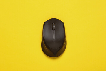 Black wireless PC mouse on a yellow background