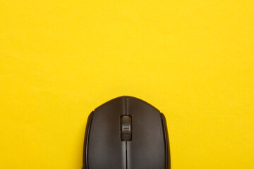 Black wireless PC mouse on a yellow background