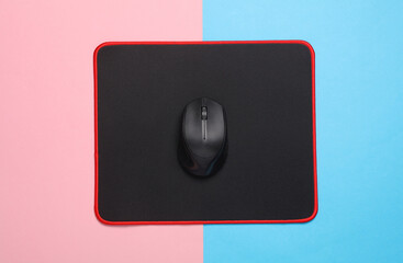 Black PC mouse with PC mouse pad on a pink blue background