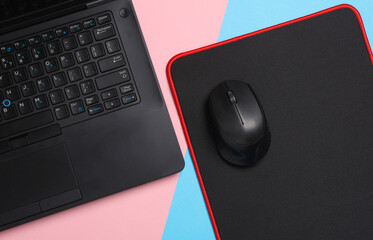 Black Laptop and PC mouse with PC mouse pad on a pink blue background