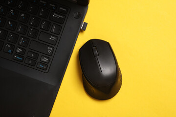 Black Laptop and wireless PC mouse on yellow background. Top view