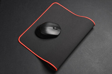 Black PC mouse with PC mouse pad on a black background