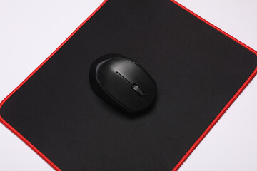 Black PC mouse with PC mouse pad on a black background