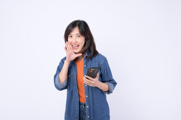 Asian woman wearing orange t shirt and denim jean is posing with a shouting gesture while holding...