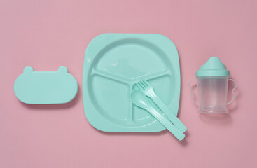 Set of plastic dishes for feeding baby on pink background. Top view