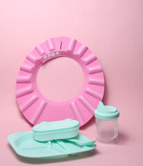 Plastic dishes for feeding a baby on a pink background
