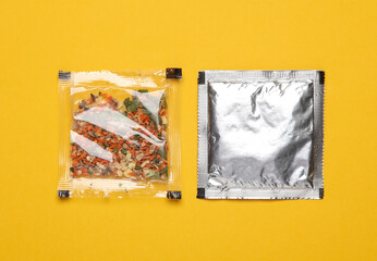 Disposable spice packets on a yellow background.