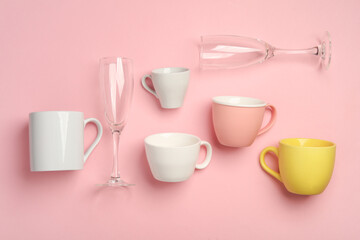 Assorted ceramic cups and glasses on a pink background. Top view