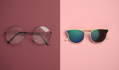 Stylish eyeglasses and sunglasses on burgundy pink background