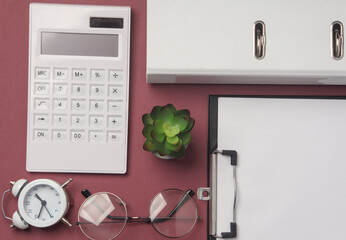Flat lay composition of office supplies on a burgundy background. Top view