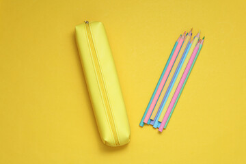 School pencil case with colored pencils on a yellow background. Back to school concept