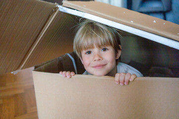 Little boy having fun with cardboard box. Playful childhood.child inside the cartoon box.