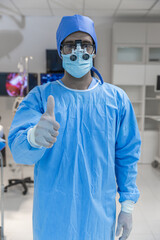 Portrait of doctor in glasses looking at camera while standing in operating room. Man surgeon in sterile gloves