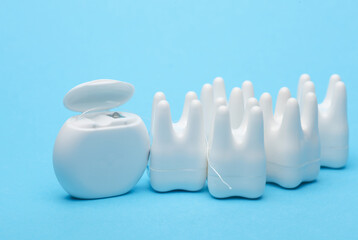 Plastic models of teeth and dental floss on a blue background. Dental care