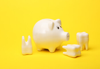 Piggy bank with models of teeth on a yellow background